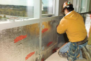 Curtain wall insulation being installed by man in yellow hard hat